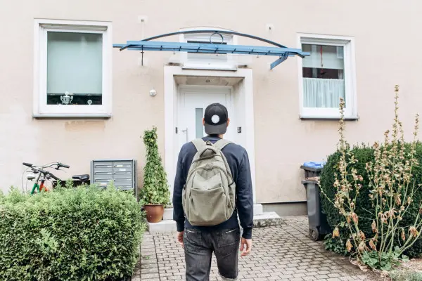 Young person facing a home in front of them