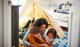 Mum reading books to dauger and son in an indoor play tent