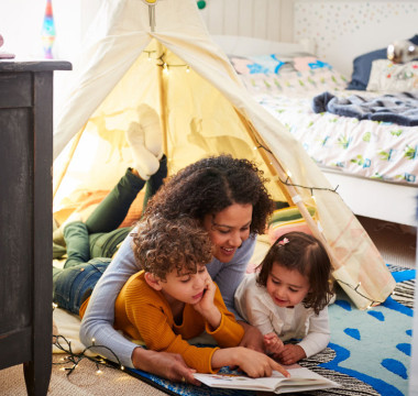 Mum reading books to dauger and son in an indoor play tent