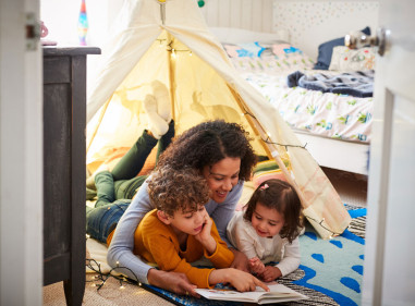 Mum reading books to dauger and son in an indoor play tent
