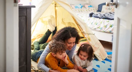 Mum reading books to dauger and son in an indoor play tent