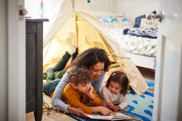 Mum reading books to dauger and son in an indoor play tent