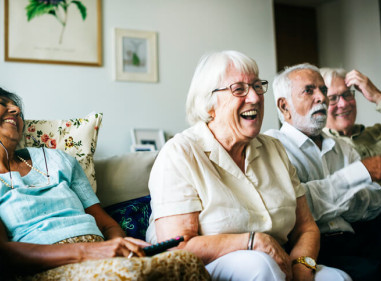 Four joyful older people reacting to an event from, the couch