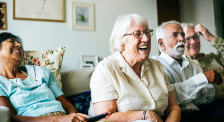 Four joyful older people reacting to an event from, the couch