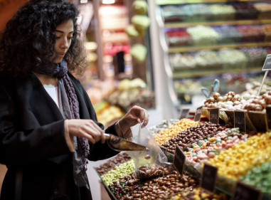 Young woman selecting fruit from a supermarket display that is full of colourful options.