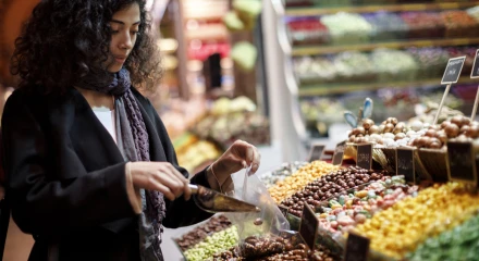 Young woman selecting fruit from a supermarket display that is full of colourful options.