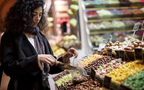 Young woman selecting fruit from a supermarket display that is full of colourful options.