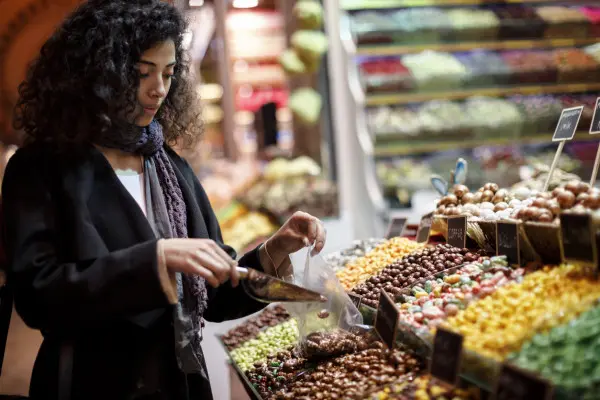 Young woman selecting fruit from a supermarket display that is full of colourful options.