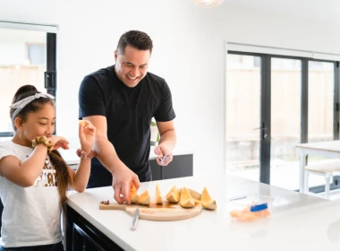 Dad and daugher eating watermelon at the kitchen bench