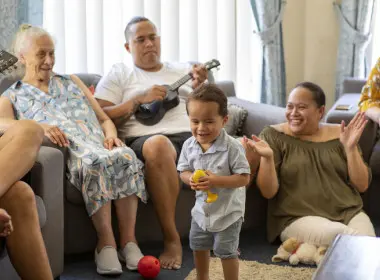 Multi-generational family enjoying singing, playing ukelele and dancing together in a living room