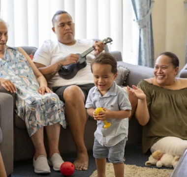 Multi-generational family enjoying singing, playing ukelele and dancing together in a living room