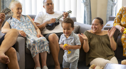 Multi-generational family enjoying singing, playing ukelele and dancing together in a living room