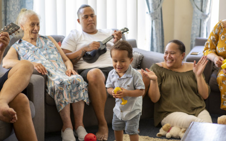 Multi-generational family enjoying singing, playing ukelele and dancing together in a living room
