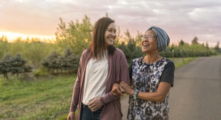 Two woman with arms linked smiling and walking at dusk