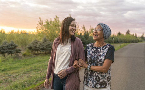 Two woman with arms linked smiling and walking at dusk