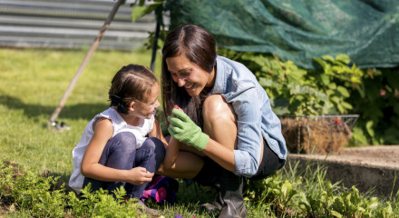 Young mother and daugher inspecting seeds while gardening