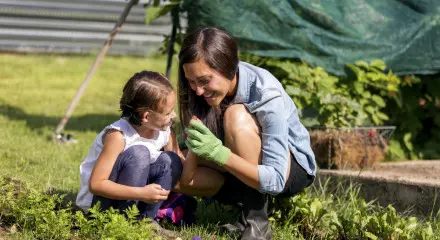 Young mother and daugher inspecting seeds while gardening