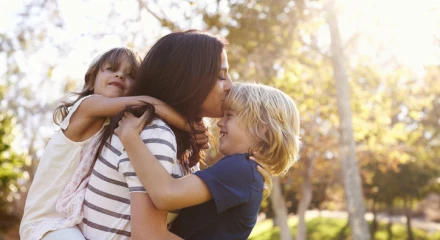 Woman cherishes moment with young children hugging her from the front and back