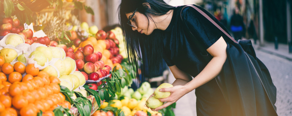 Young woman selecting fruit from a colourful market display