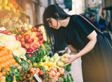 Young woman selecting fruit from a colourful market display