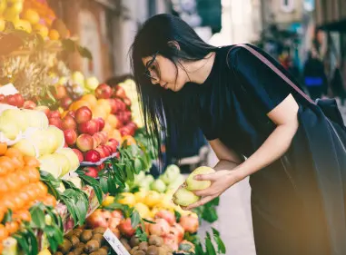 Young woman selecting fruit from a colourful market display