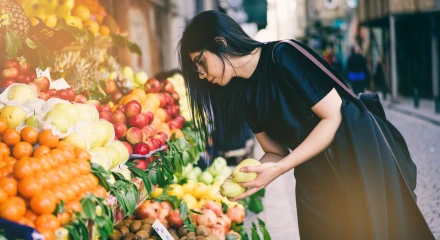 Young woman selecting fruit from a colourful market display