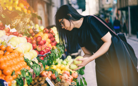 Young woman selecting fruit from a colourful market display
