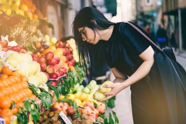 Young woman selecting fruit from a colourful market display