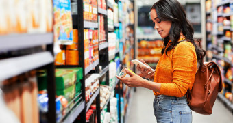 Person is holding a can of food in the supermarket aisle and looking at the ingredient list.