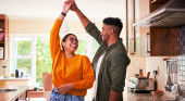 Blog 2022.04.05 How to deal with rising mortgage rates Couple are dancing in the kitchen and looking at each other laughing