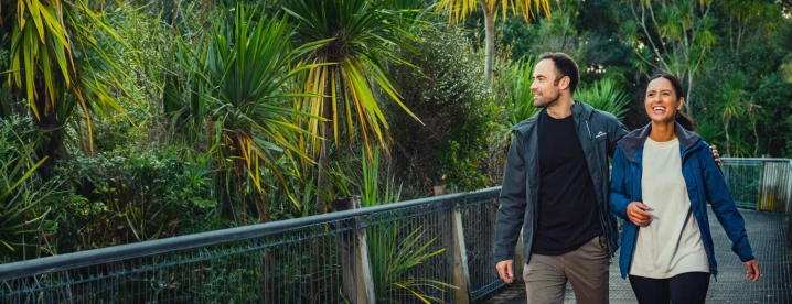 A man and woman are walking together outdoors and looking happy