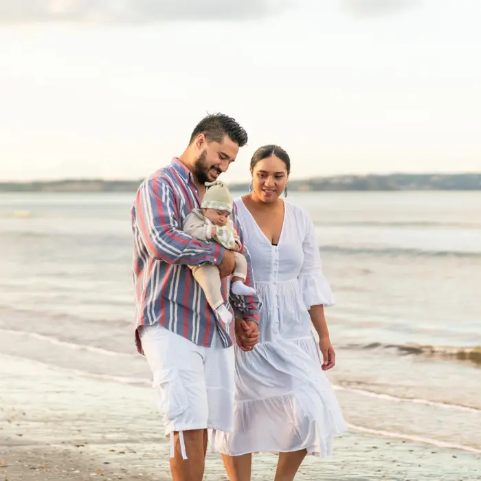 Couple with baby walking down the beach