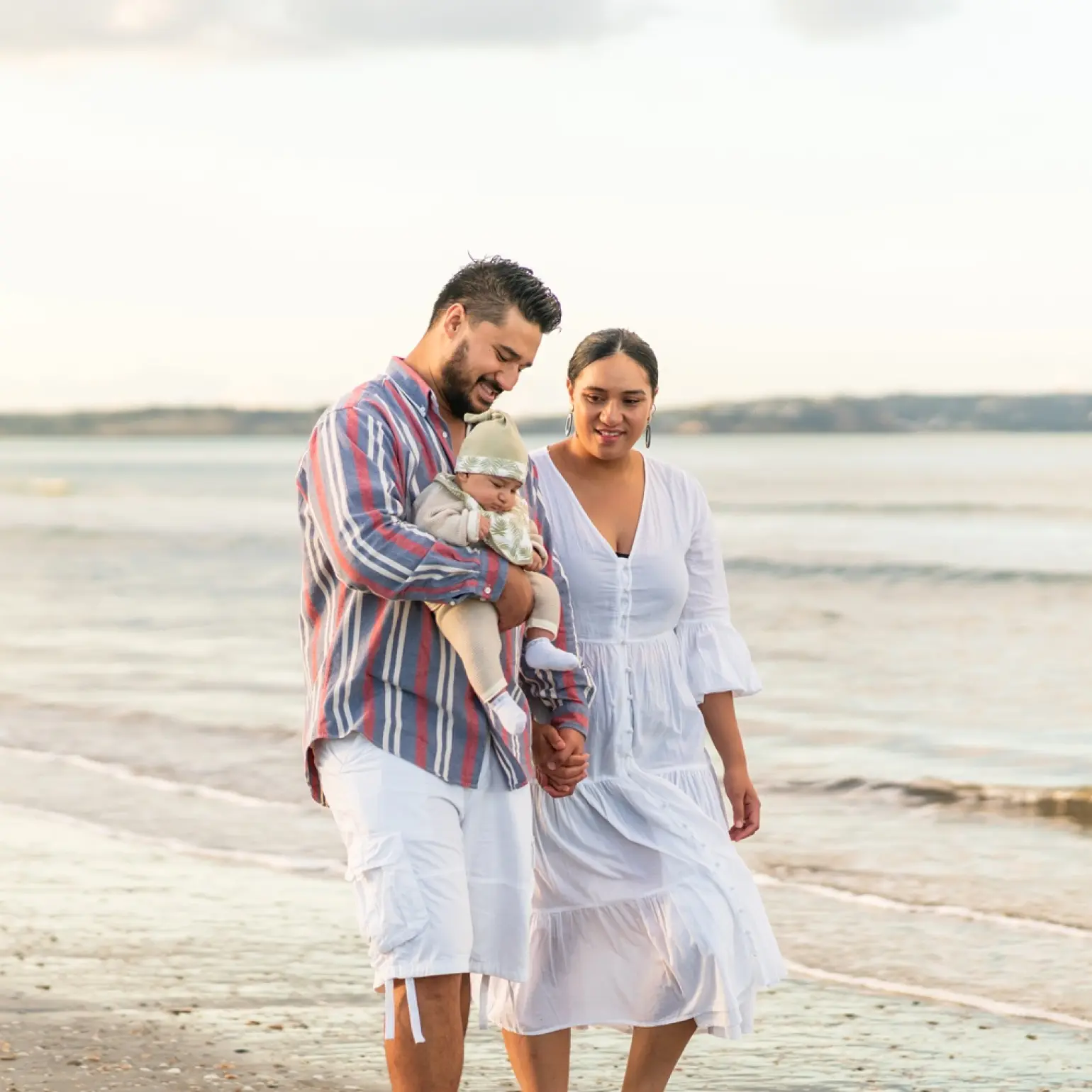 Couple with baby walking down the beach