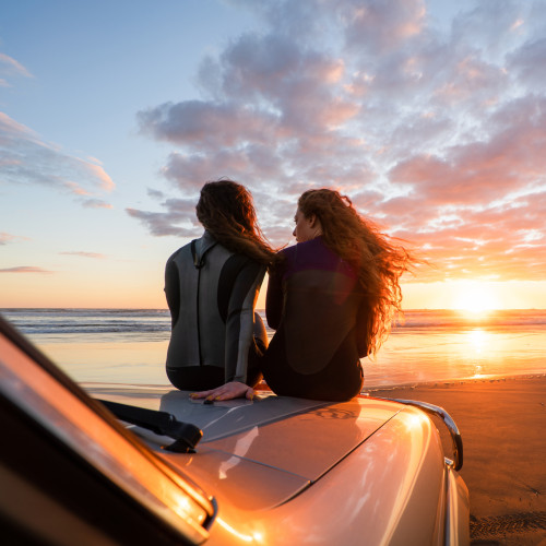 Two women on truck at beach 