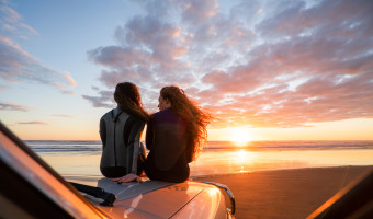 Two women on truck at beach