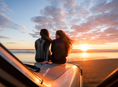 Two women on truck at beach 