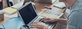 Person working on laptop over a desk with a coffee.