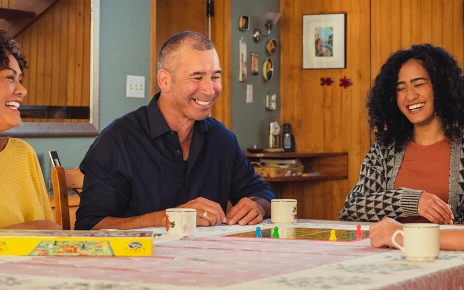 A family are sitting at a table playing snakes and ladders