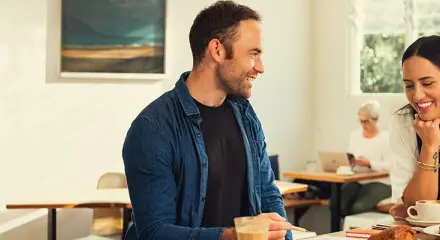 A man and woman are sitting together at a table in a cafe