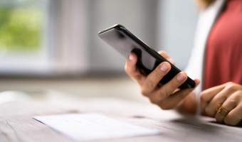 Hand holding a phone learning about frauds and how to avoid scams