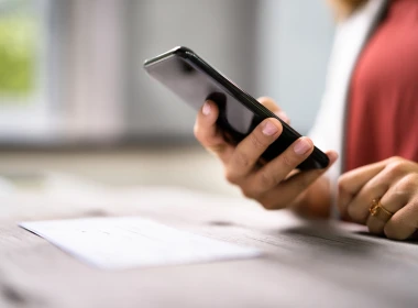 Hand holding a phone learning about frauds and how to avoid scams