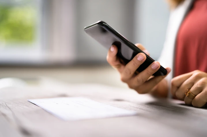 Hand holding a phone learning about frauds and how to avoid scams