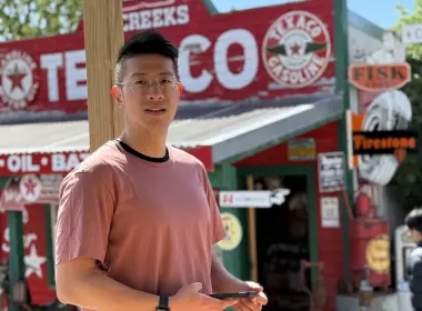 Evan standing holding his phone looking at camera