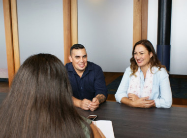 Couple smiling talking to woman over a desk
