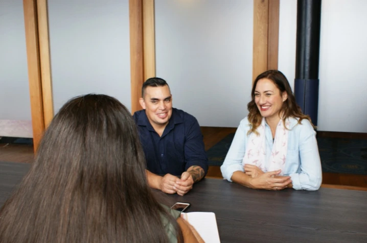 Couple smiling talking to woman over a desk