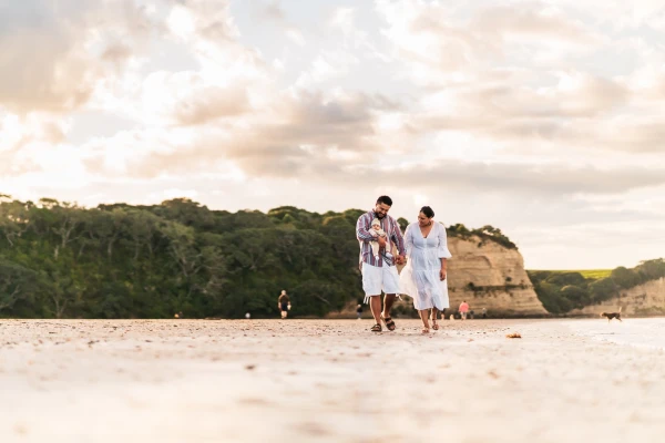 Family of three walking down a NZ beach talking about their why for having emergency savings