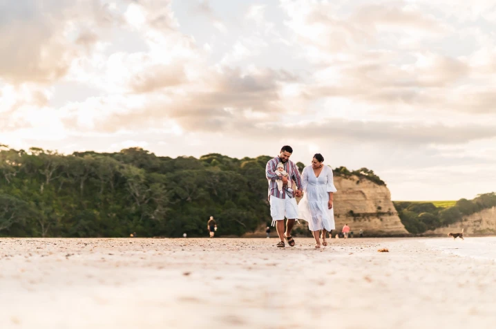 Family of three walking down a NZ beach talking about their why for having emergency savings