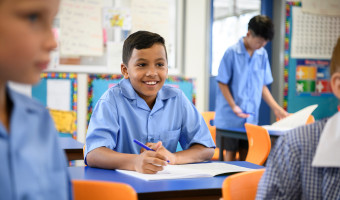 Child sitting in classroom smiling.