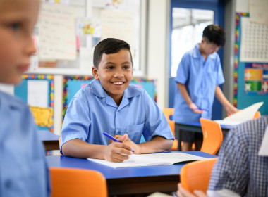 Child sitting in classroom smiling.