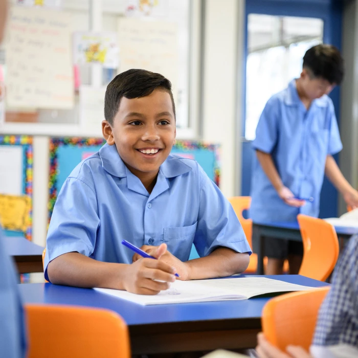 Child sitting in classroom smiling.